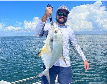 Captain Joey Nadotti holding a silvery pompano on the water