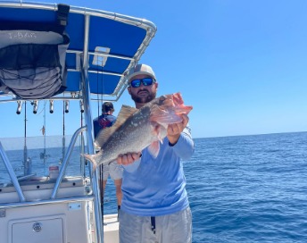 Captain Jonallen Velazquez holding up a fresh catch aboard a center-console boat offshore