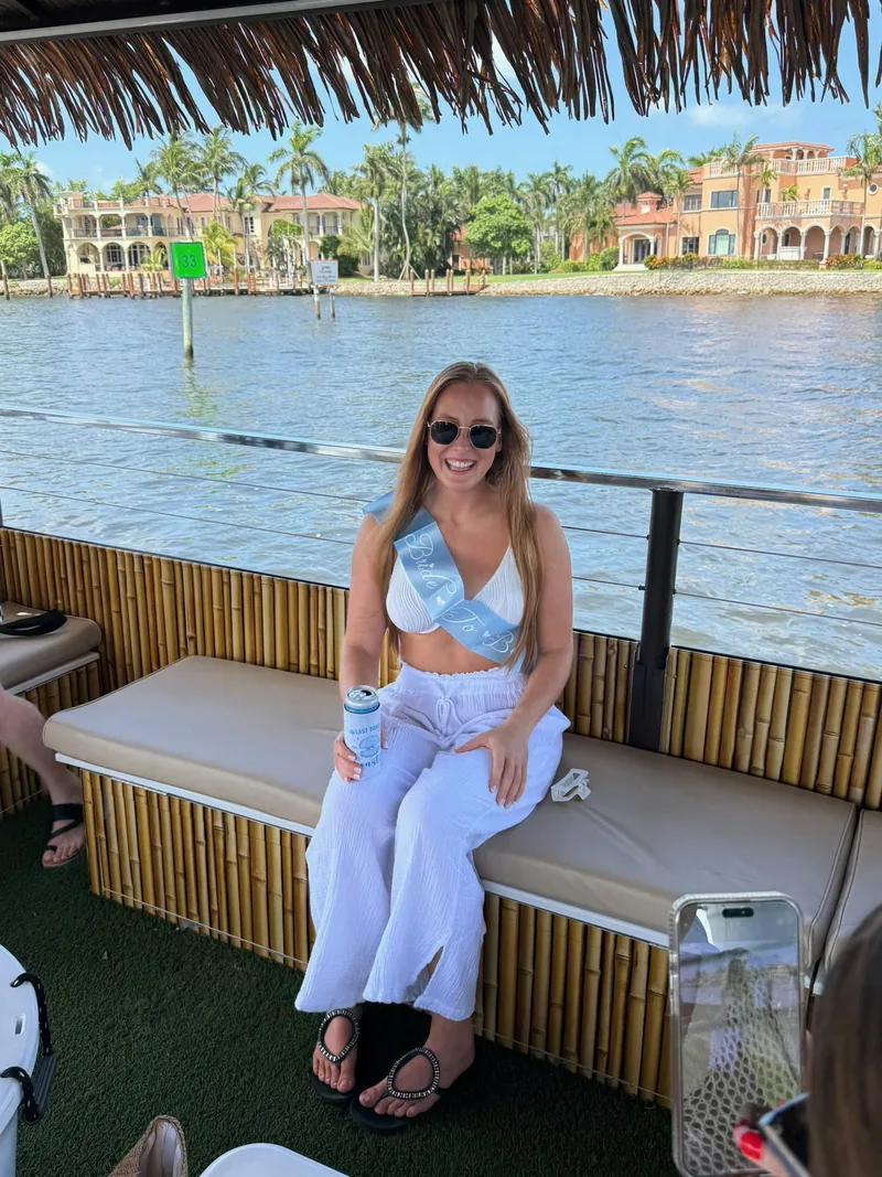 The bride-to-be with her sash on the bamboo bench as the boat cruises past waterfront estates