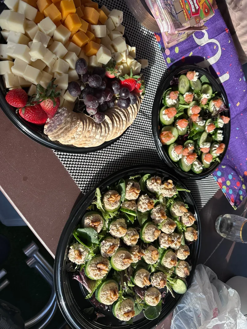 Catering trays aboard the boat with cubed cheeses, fruit, crackers and cucumber appetizer bites