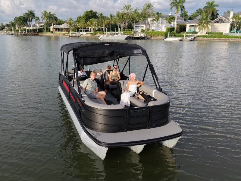 A small group of guests aboard the Evotti luxury pontoon on a canal lined with waterfront homes