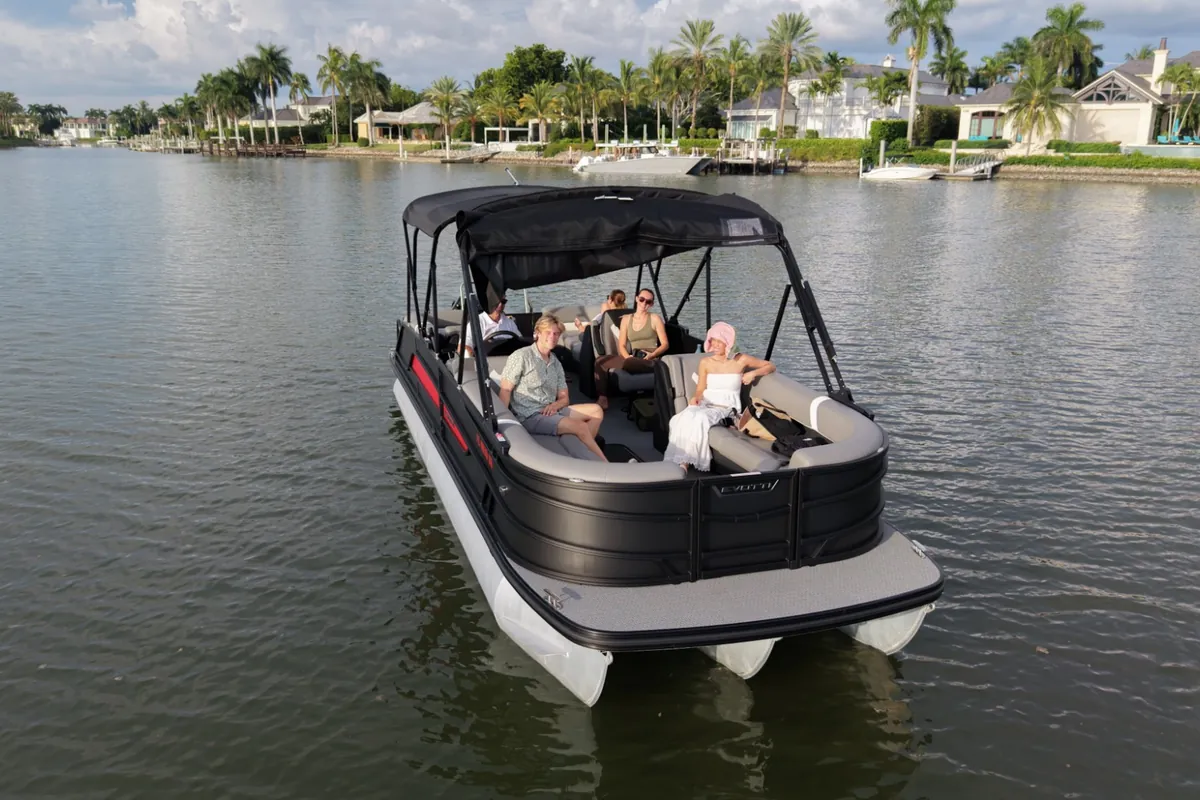 A small group of guests aboard the Evotti luxury pontoon on a canal lined with waterfront homes