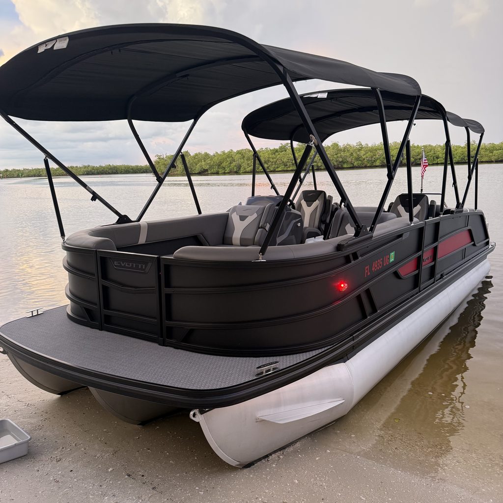 The Evotti, a Sand Dollar luxury pontoon, pulled up on a sandy beach with mangroves behind at sunset