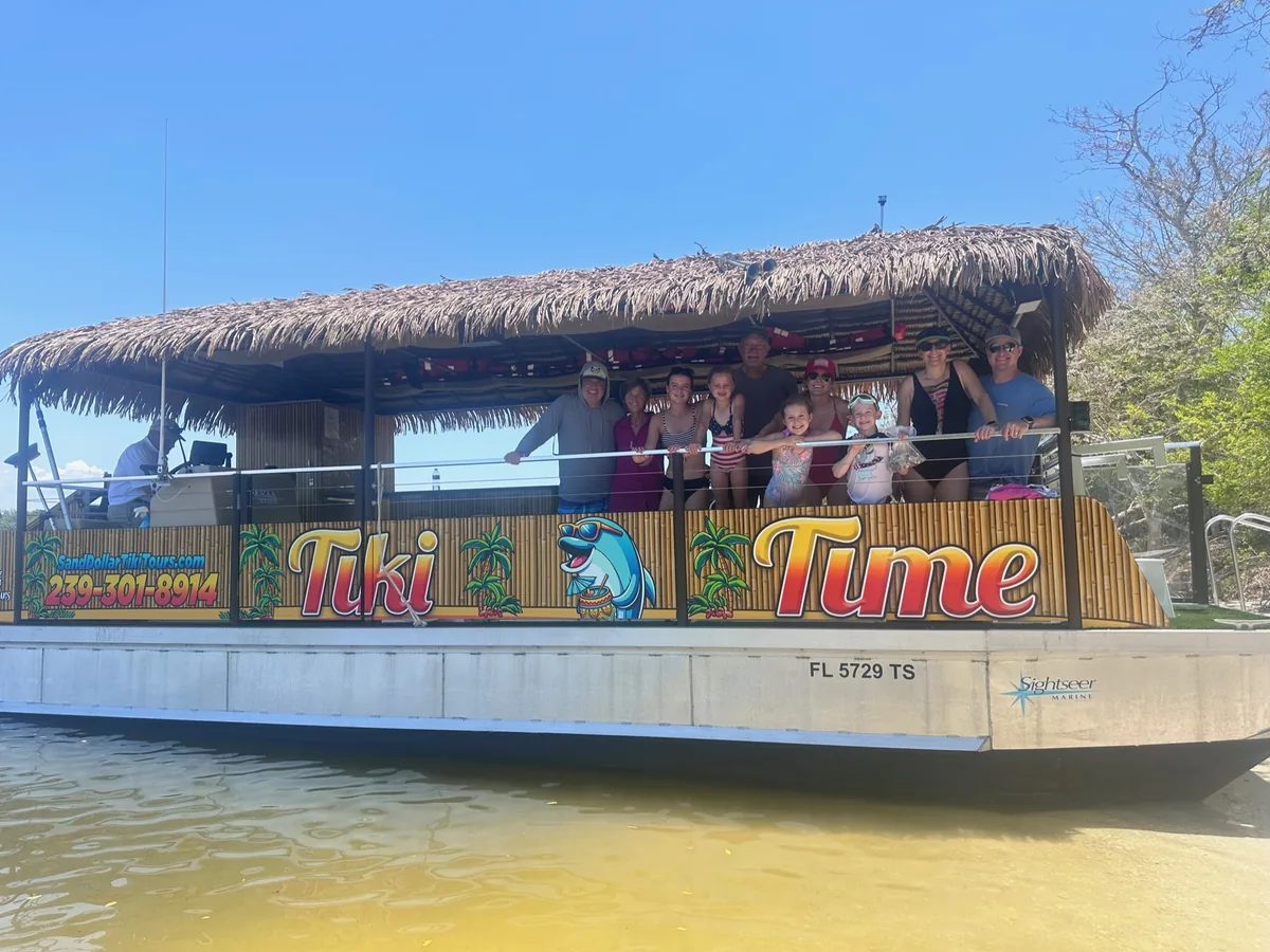 A multigenerational family waving from the rail of the Tiki Time boat on a sunny Marco Island waterway