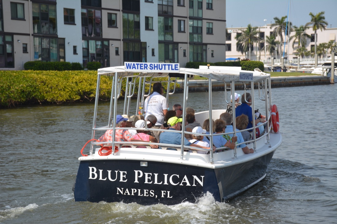 The Blue Pelican water shuttle full of guests cruising Naples Bay past the downtown Naples waterfront in Florida