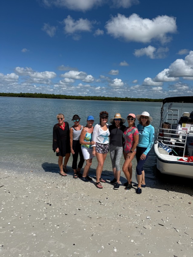 A group relaxing on a Ten Thousand Islands sandbar beside a Sand Dollar boat, Marco Island