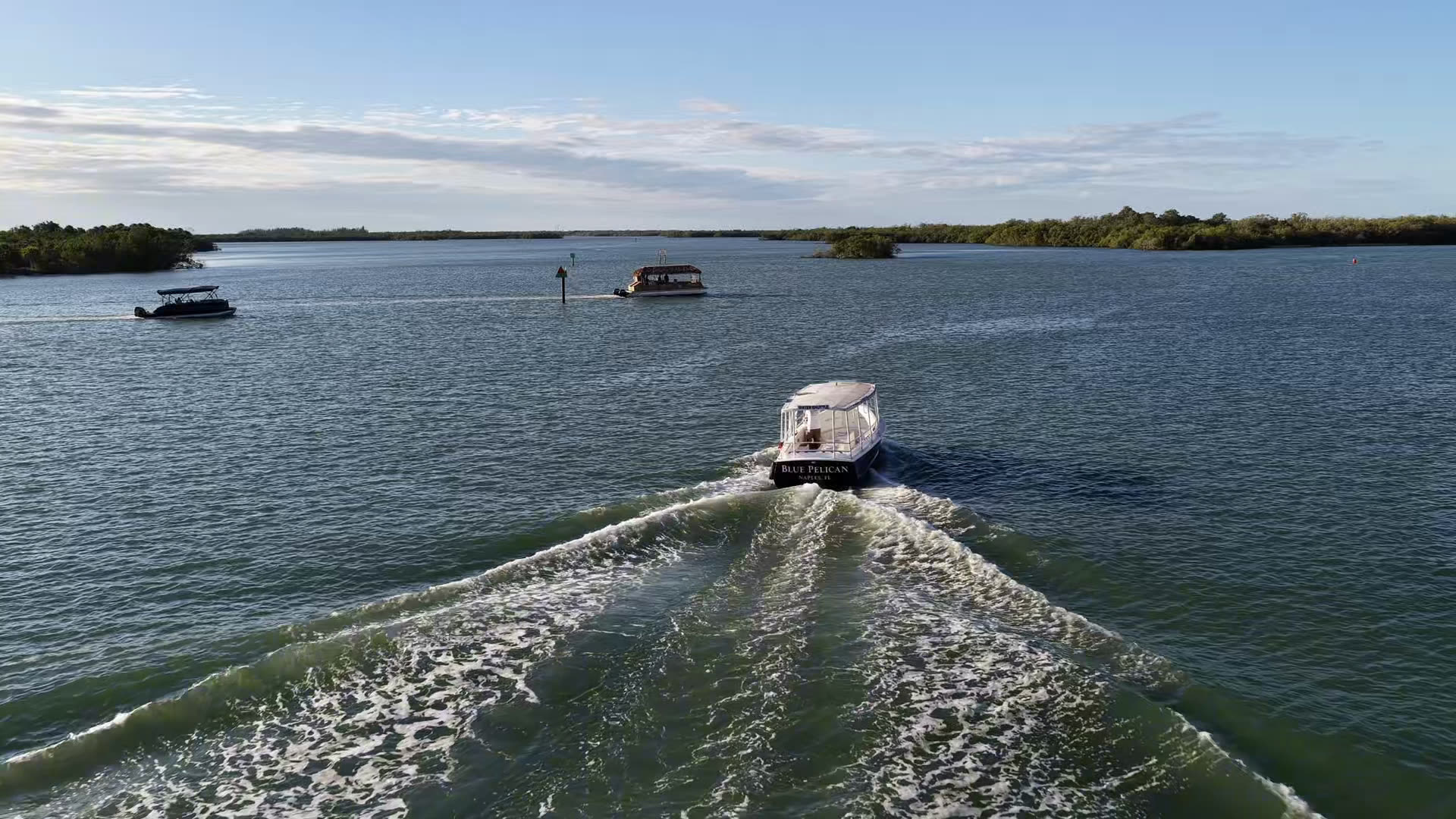Sand Dollar drone footage: the Blue Pelican water shuttle heading out across the bay, sandbars below the Marco Island skyline, and three boats running together