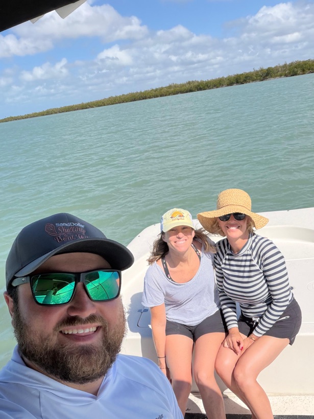 A Sand Dollar captain at the wheel with two guests seated aboard the boat on calm green water near Naples, Florida