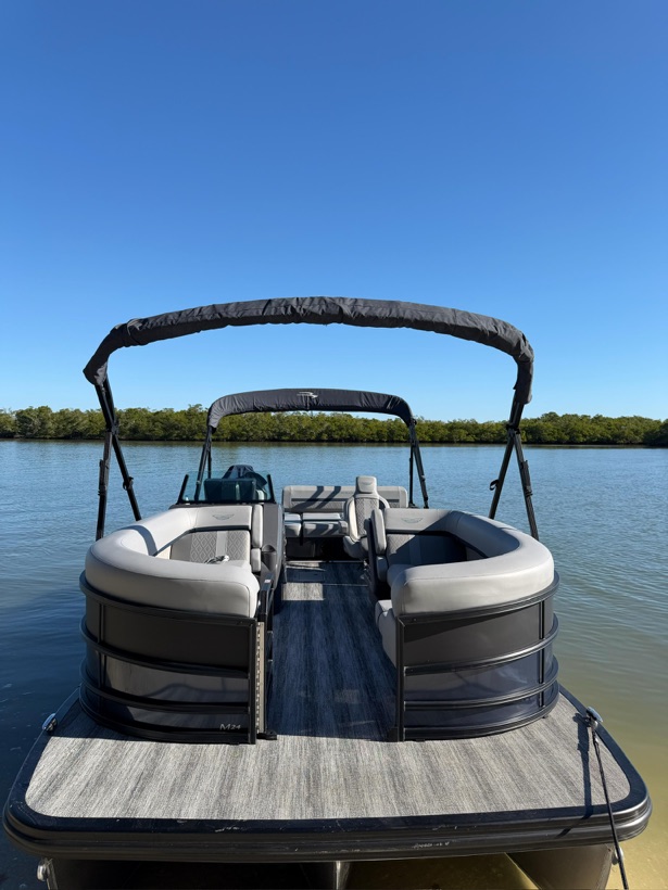 A Sand Dollar charter boat with shaded seating tied up in calm mangrove-lined water near Naples, Florida