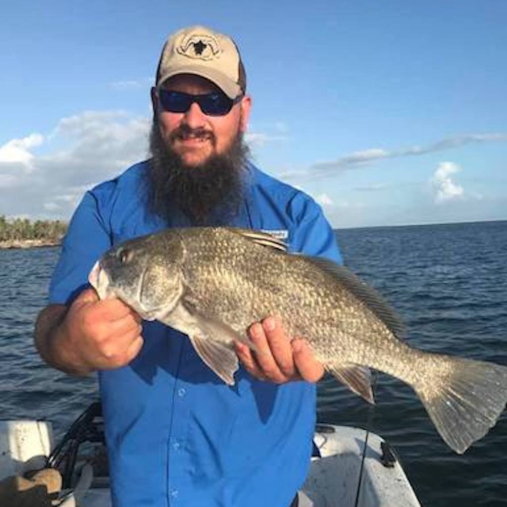 An angler holding a fish caught on a licensed Sand Dollar charter in the calm backwater near Naples, Florida