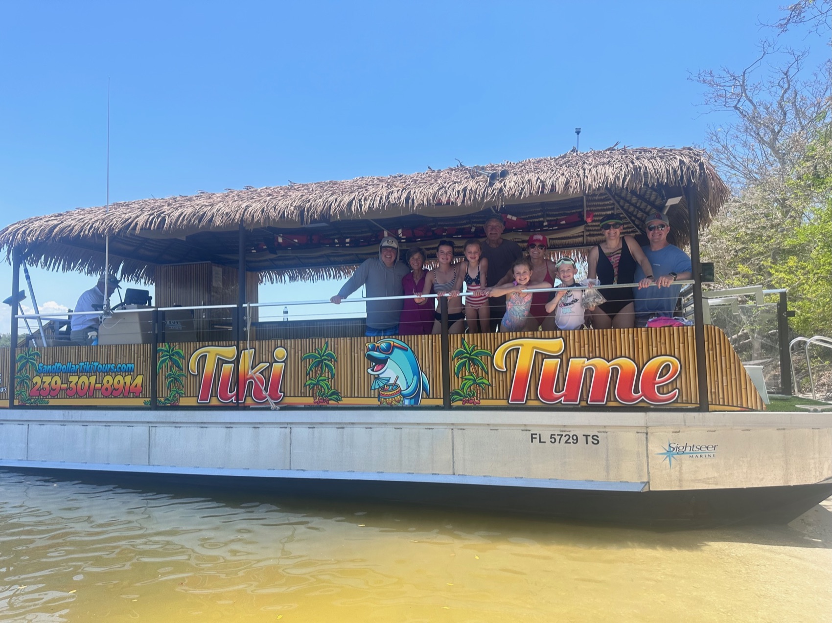 The thatched-roof Sand Dollar tiki boat cruising calm water near Naples, Florida, with shaded seating and safety rails all around