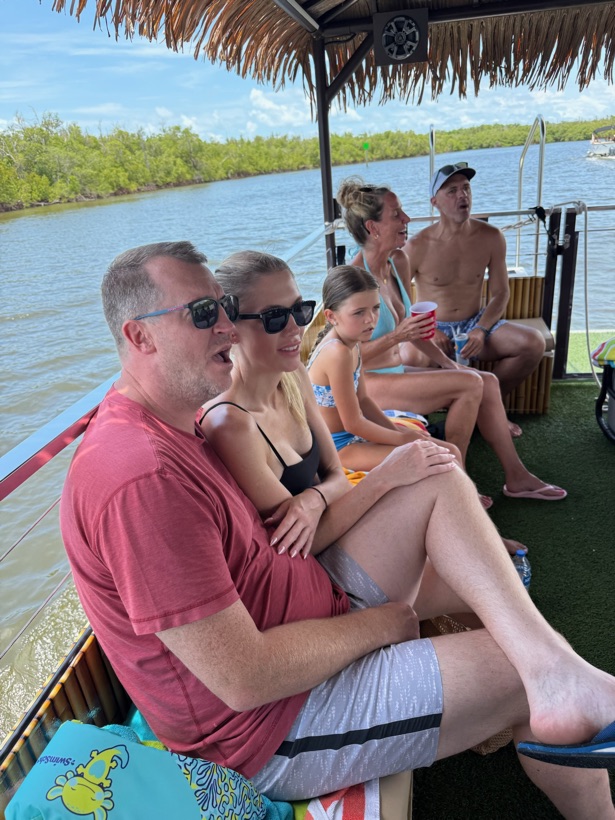 Guests relaxing in the shade aboard the Sand Dollar tiki boat on calm water near Naples, Florida