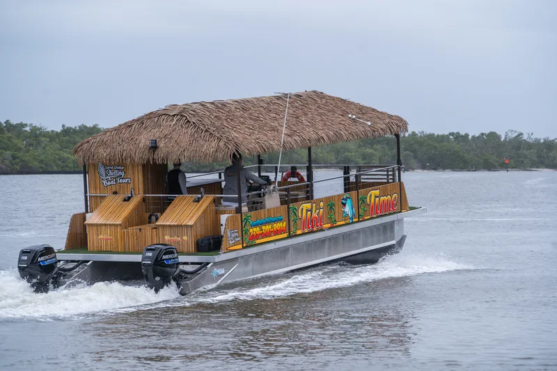 The Tiki Time tiki boat cruising a mangrove-lined channel with its wake trailing behind